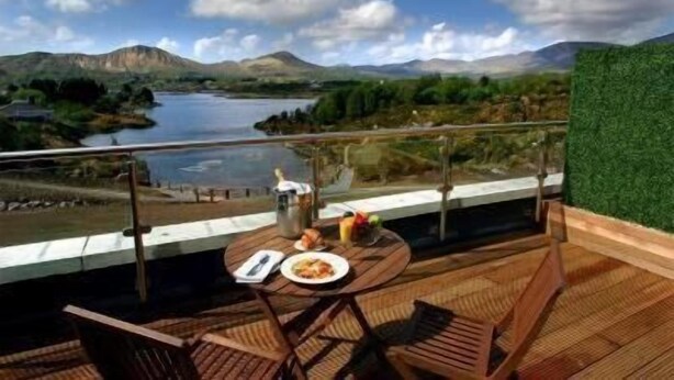A balcony with a table set for two, overlooking a lake and mountains. - Sneem Hotel (Sneem)