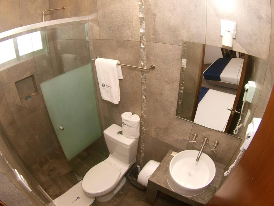 A modern bathroom with a glass-enclosed shower, a toilet, a sink, and a mirror.