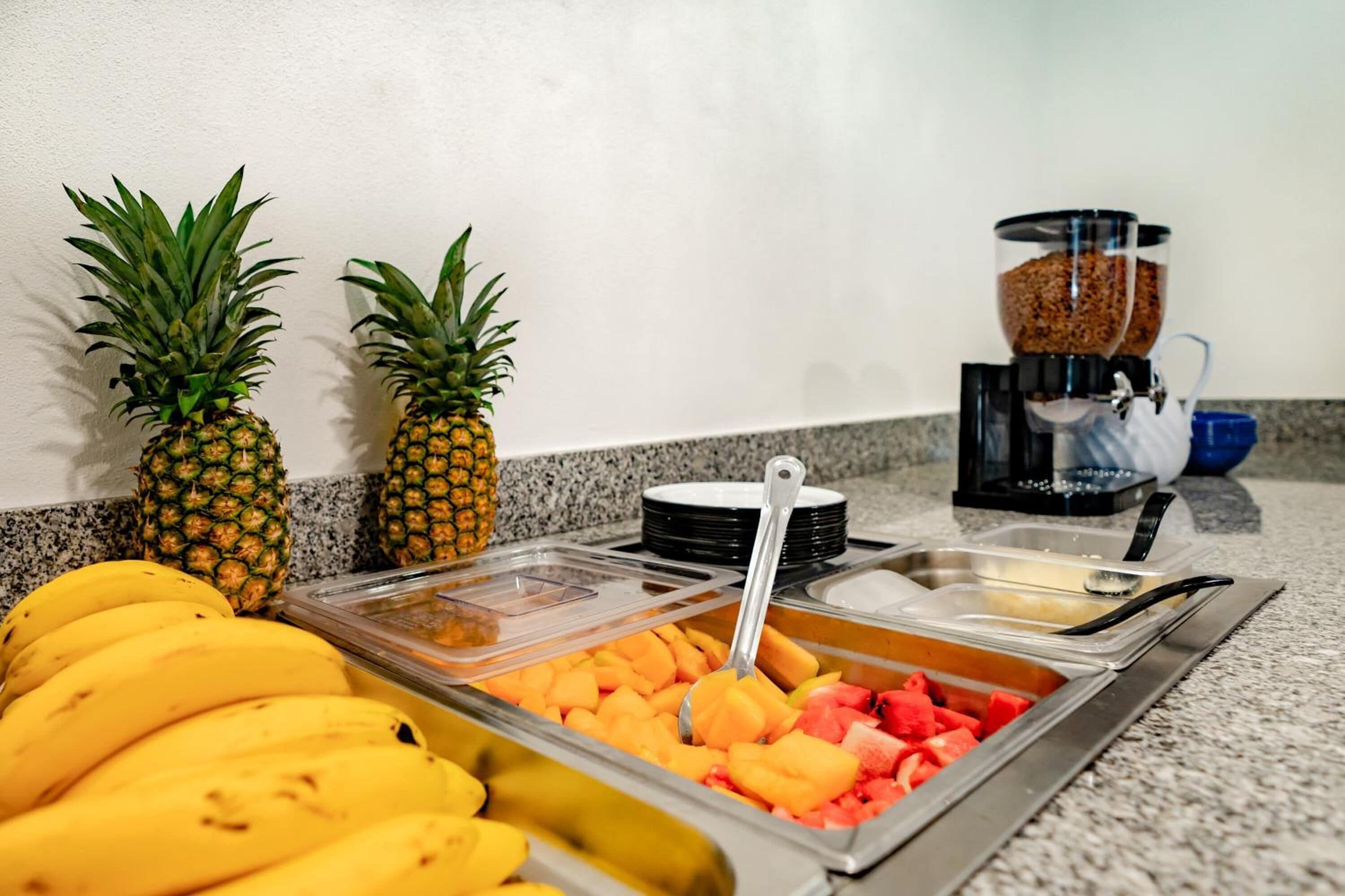 A buffet with bananas, pineapple, and various fruits.