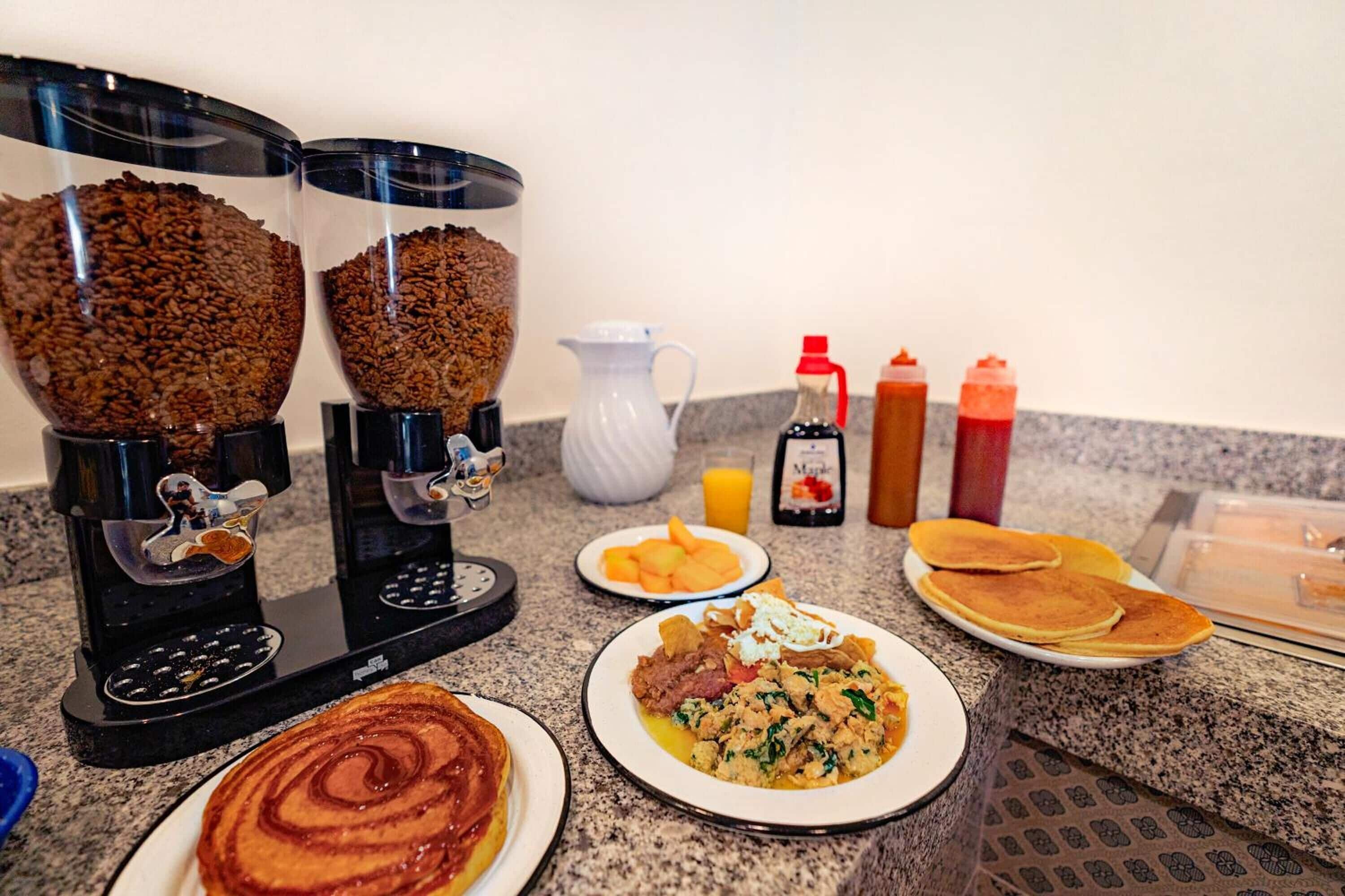 A breakfast setup with a coffee maker, a pitcher, and various condiments.