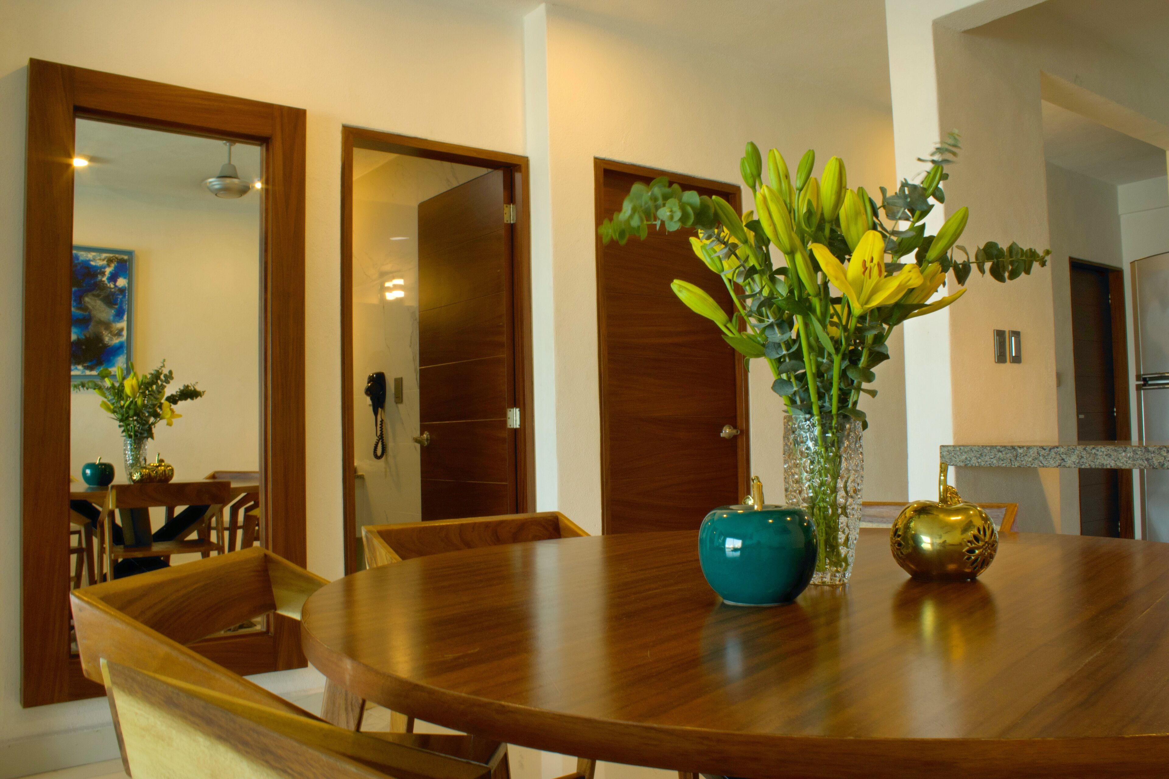 A dining area with a round wooden table, chairs, and a vase with flowers.