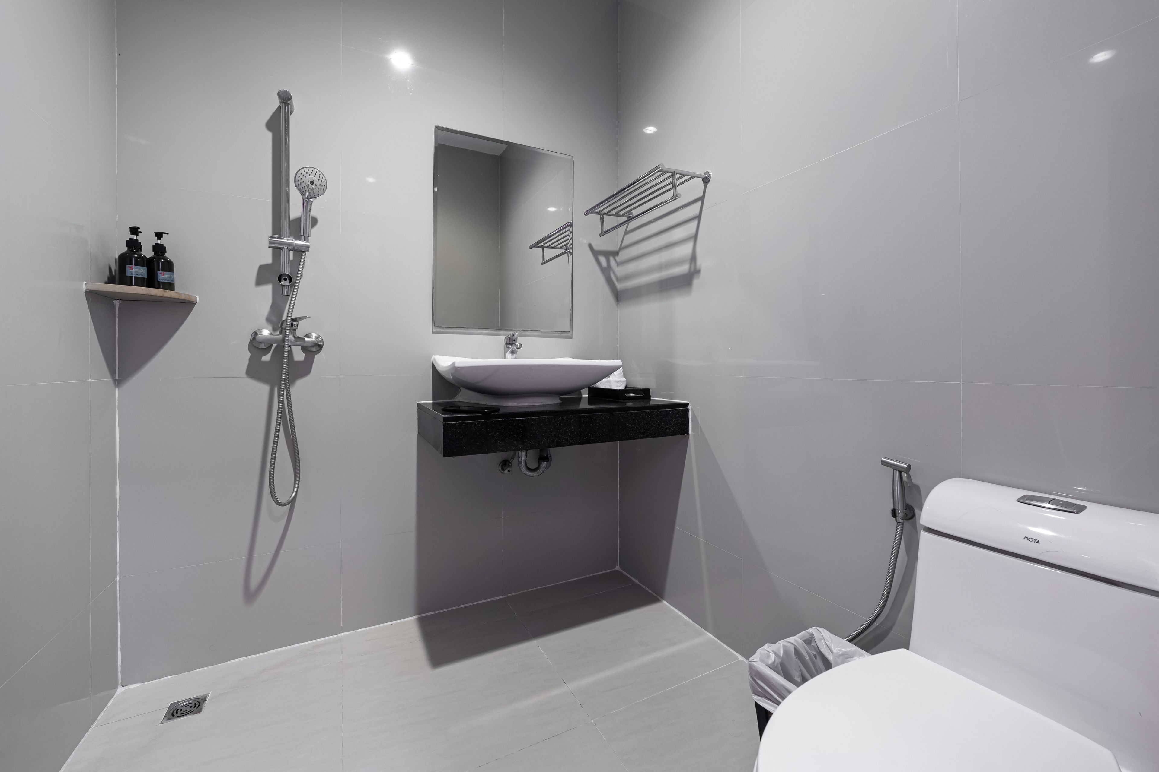 Un baño moderno con un lavamanos blanco, un espejo, una ducha y un inodoro.