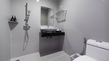 Un baño moderno con un lavamanos blanco, un espejo, una ducha y un inodoro.
