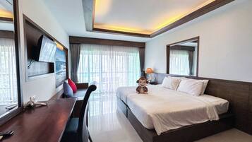 Una habitación de hotel con una cama, un escritorio, una silla, un televisor montado en la pared y un espejo grande.
