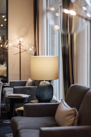 Un rebedor d'hotel modern amb una finestra gran, una làmpada de peu i un sofà.