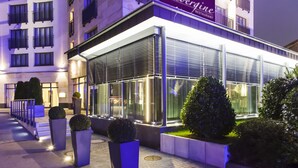 A modern building with a glass facade, outdoor seating area, and well-maintained landscaping. - Hotel Vier Jahreszeiten Starnberg (Starnberg)