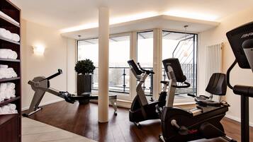 A modern fitness room with cardio equipment, a large window, and a view of the city.