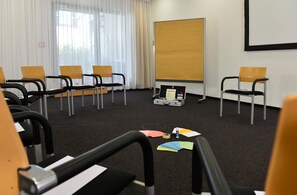 Une salle de conférence équipée d’un tableau blanc, de chaises et d’un projecteur.