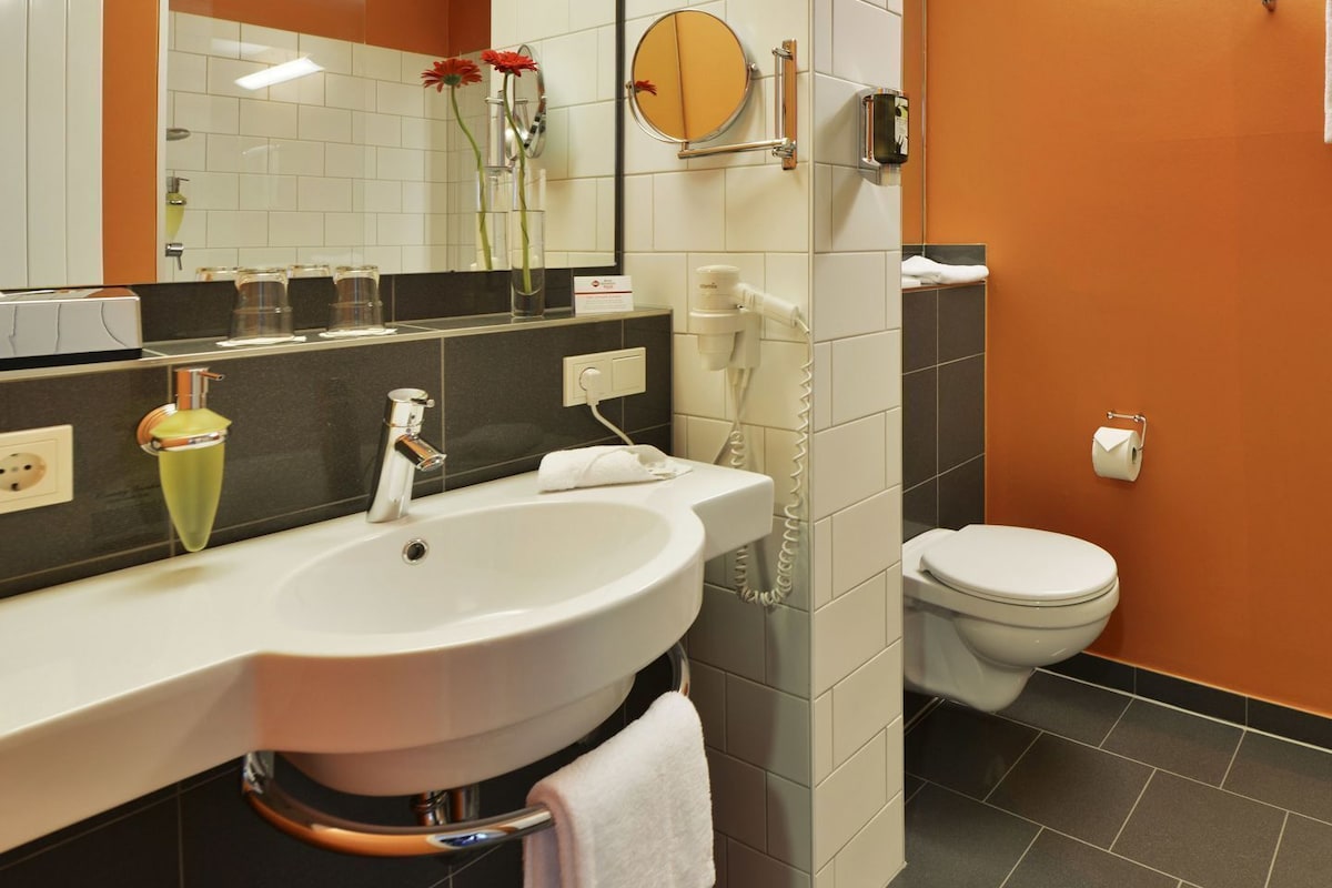 A bathroom with a white sink, mirror, and toilet.