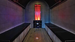 Un pasillo moderno, tenuemente iluminado, con una columna central que presenta un panel iluminado en rojo y azul.