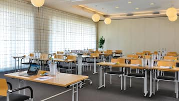 Kokoushuone, jossa on pöytiä, tuoleja ja projektori.