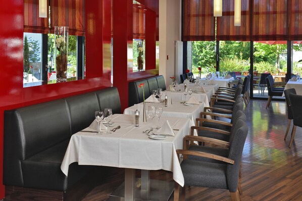 A restaurant with long tables, white tablecloths, and black leather booths. - Best Western Plus Konrad Zuse Hotel (Huenfeld)