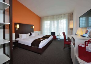 A hotel room with a large bed, a desk with a chair, a TV, and a window with curtains. - Best Western Plus Konrad Zuse Hotel (Huenfeld)
