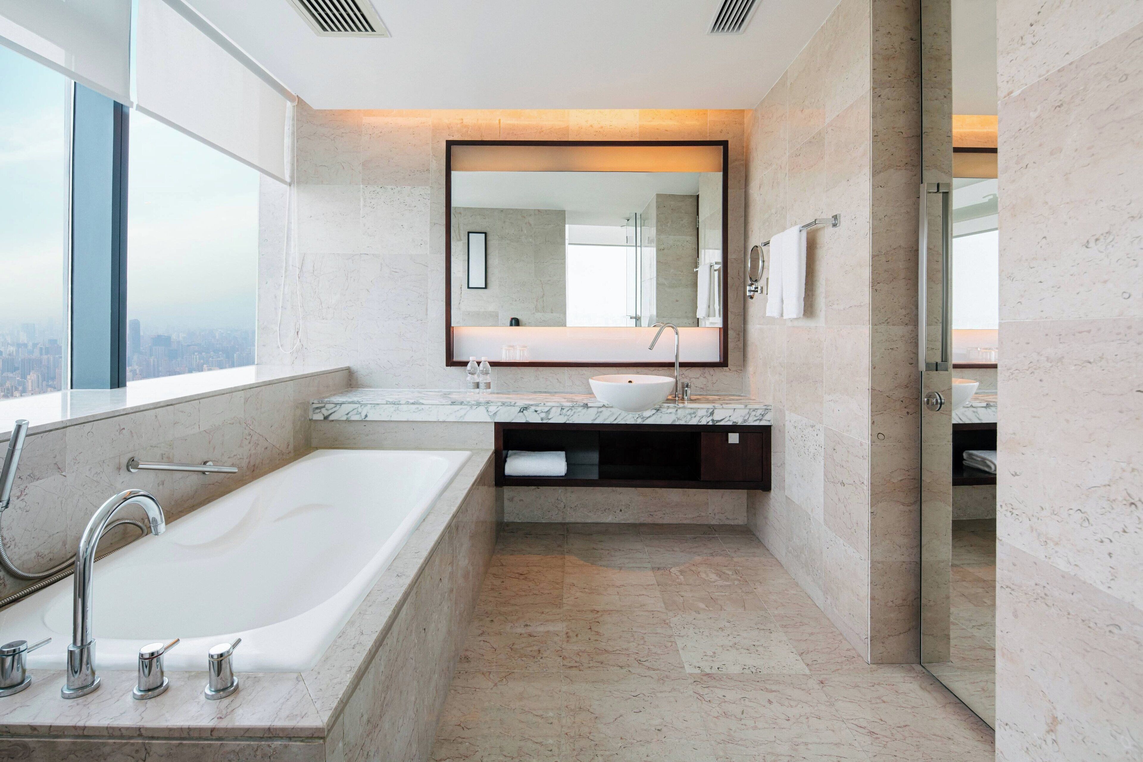 A modern bathroom with a large bathtub, a sink, and a mirror.