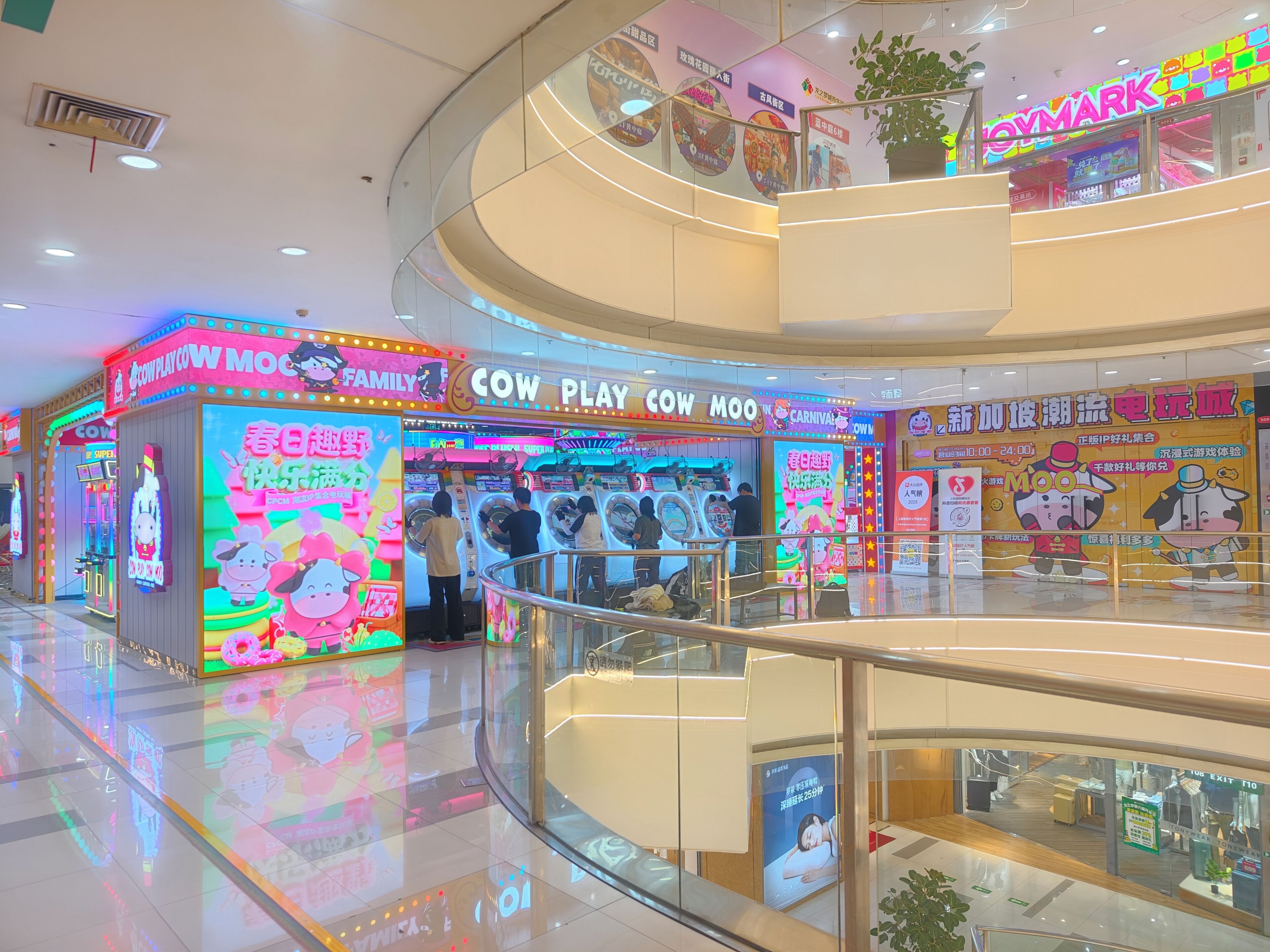 Un centro comercial de varios niveles con una zona de juegos iluminada, destacando letreros de neón y máquinas recreativas.