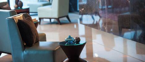 A modern lobby with a seating area, a marble reception desk, and a view through large windows.