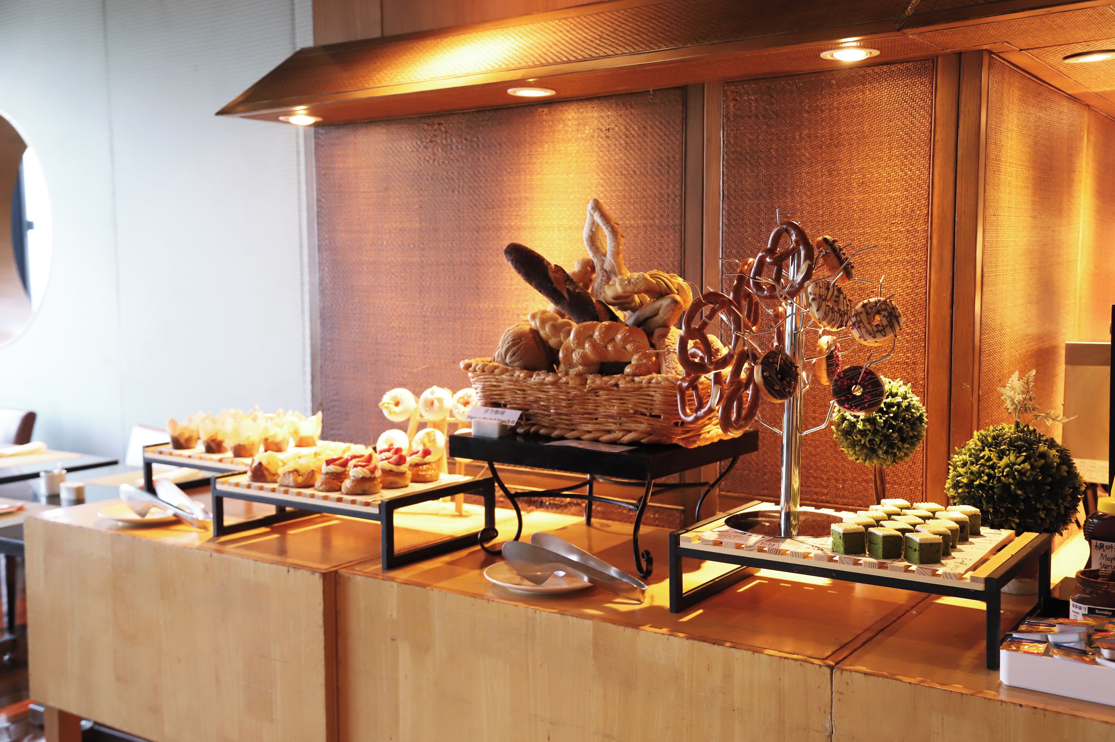 Un buffet proposant une variété de plats, notamment des pâtisseries et des desserts, disposés sur un comptoir en bois.
