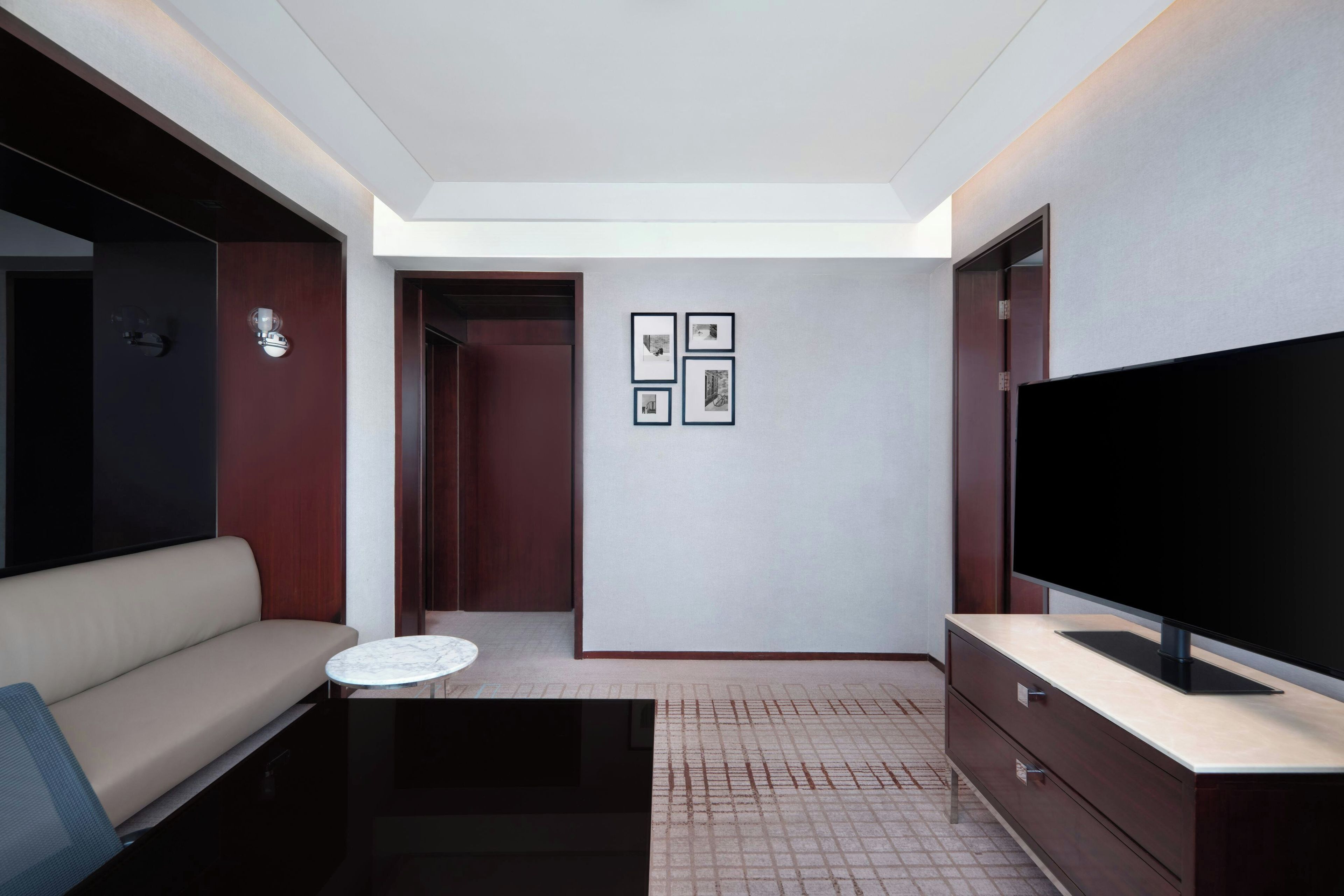 A modern living room with a sofa, a coffee table, a flat-screen TV, and a wall-mounted TV.