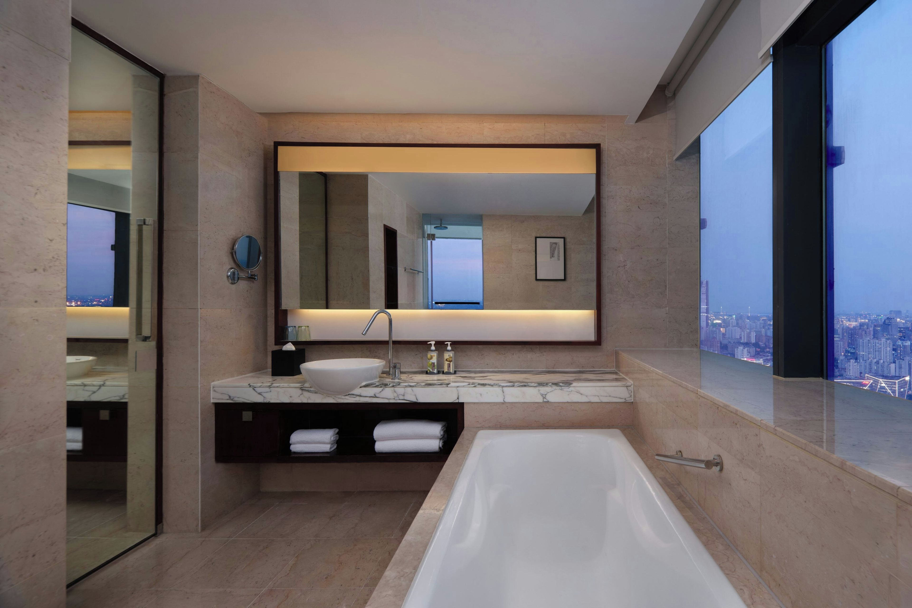 A modern bathroom with a large bathtub, a sink with a marble countertop, and a large mirror above the sink.
