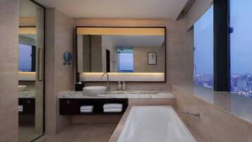 A modern bathroom with a large bathtub, a sink with a marble countertop, and a large mirror above the sink.