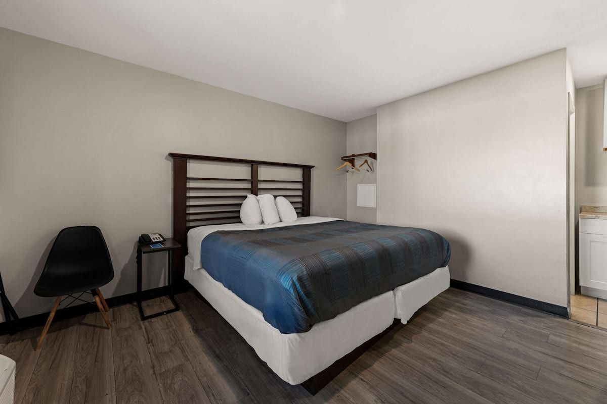 Un dormitorio con cama, una silla, una mesita de noche y un armario.