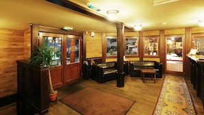 A wooden-paneled room with a large window, a bench, a small table, and a potted plant. - Boat Hotel Matylda (Prague)