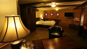 A hotel room with a bed, a wooden ceiling, a TV mounted on the wall, and a lamp. - Boat Hotel Matylda (Prague)