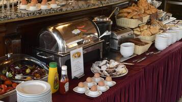 Un buffet proposant une variété de plats, notamment des fruits, du pain et des pâtisseries, disposés sur une table recouverte d’une nappe rouge.