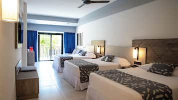 Habitación de hotel con dos camas, un escritorio y un balcón con cortinas azules.