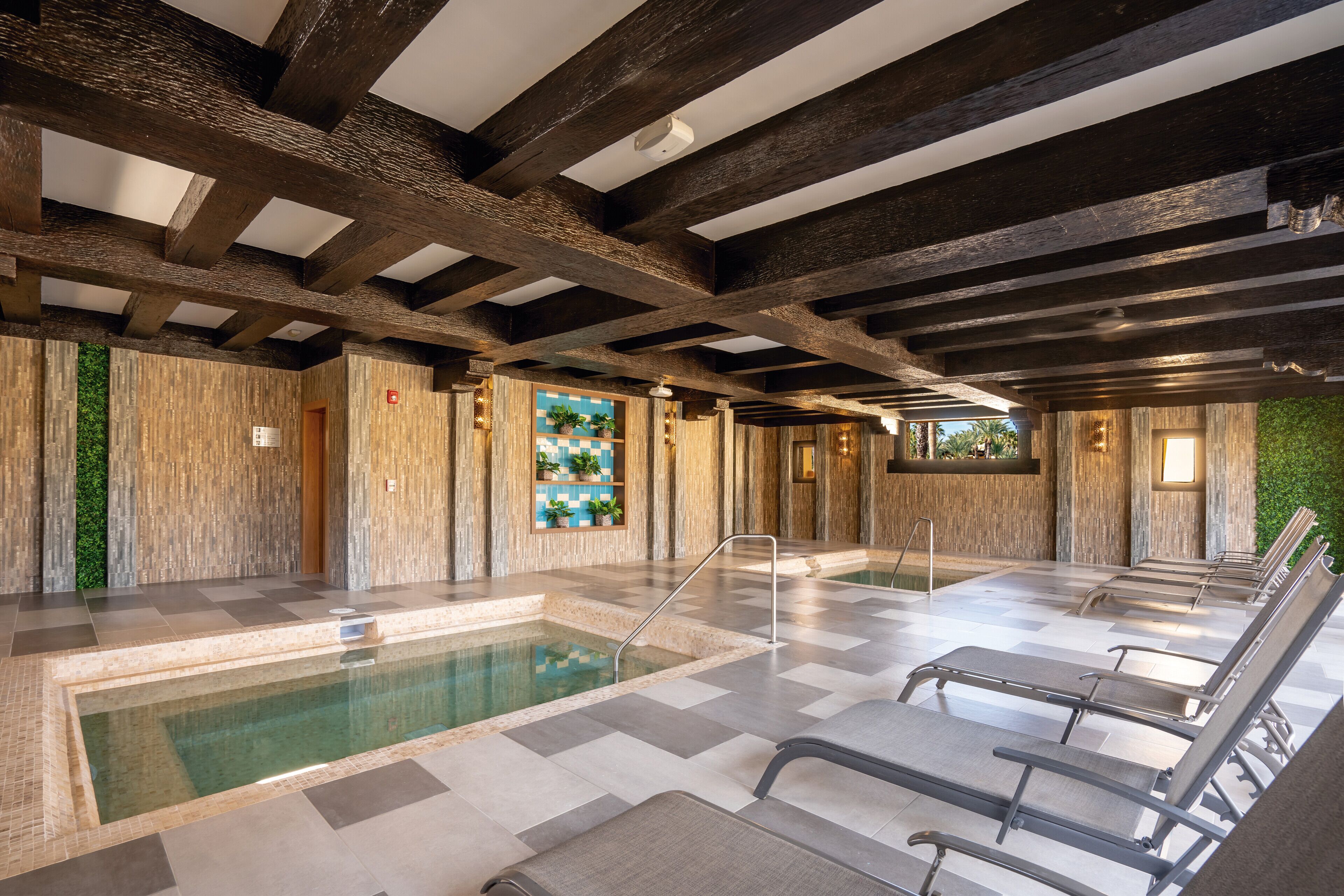 Un área de spa con piscina, sillones reclinables y techo de madera.