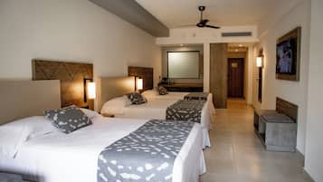 A hotel room with three beds, a ceiling fan, a large mirror, and a television.