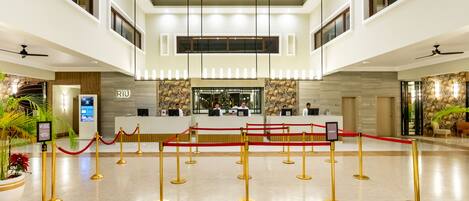 A spacious lobby with a reception desk, a check-in counter, and a red rope barrier.