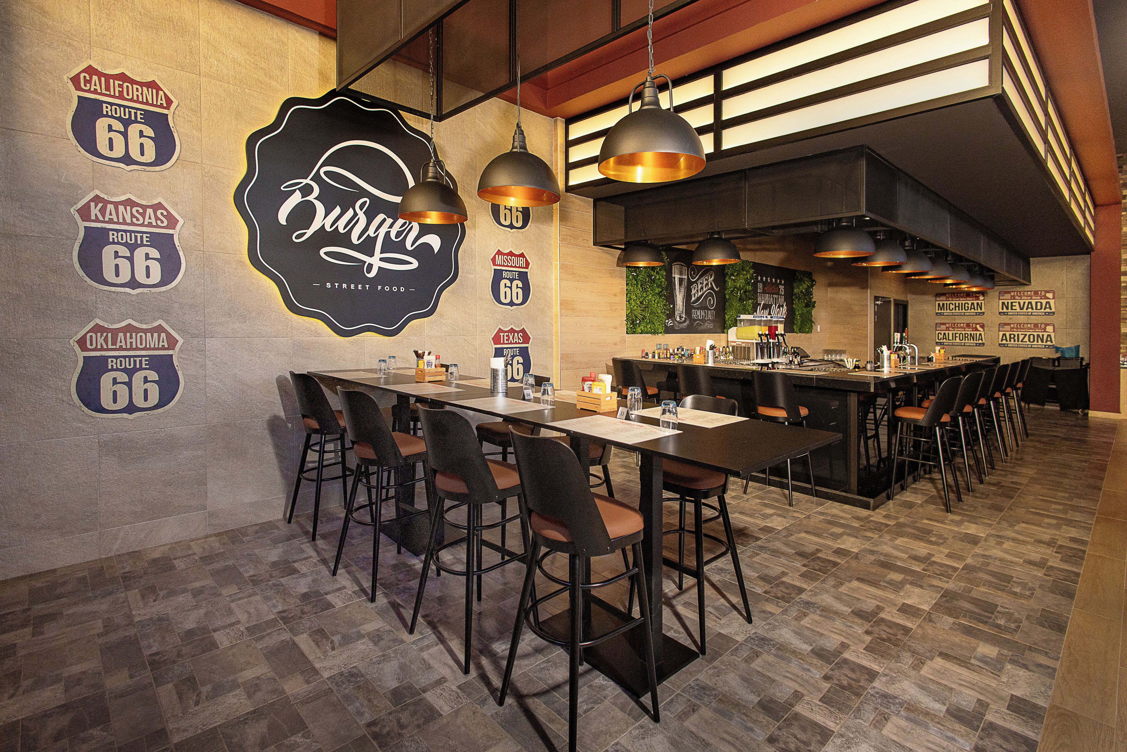 A restaurant with a long counter, multiple bar stools, and a bar area.