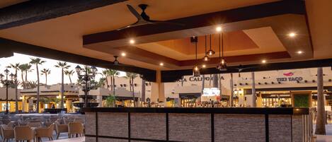 A spacious outdoor seating area with a modern bar and a Tiki Taco restaurant in the background.