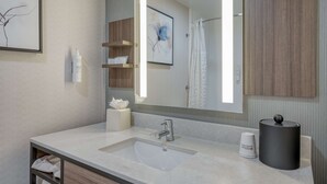 Une salle de bain moderne avec un grand miroir, un lavabo et un distributeur de serviettes.