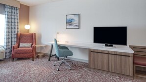 Une chambre d’hôtel équipée d’un bureau, d’une télévision, d’une chaise et d’une lampe.