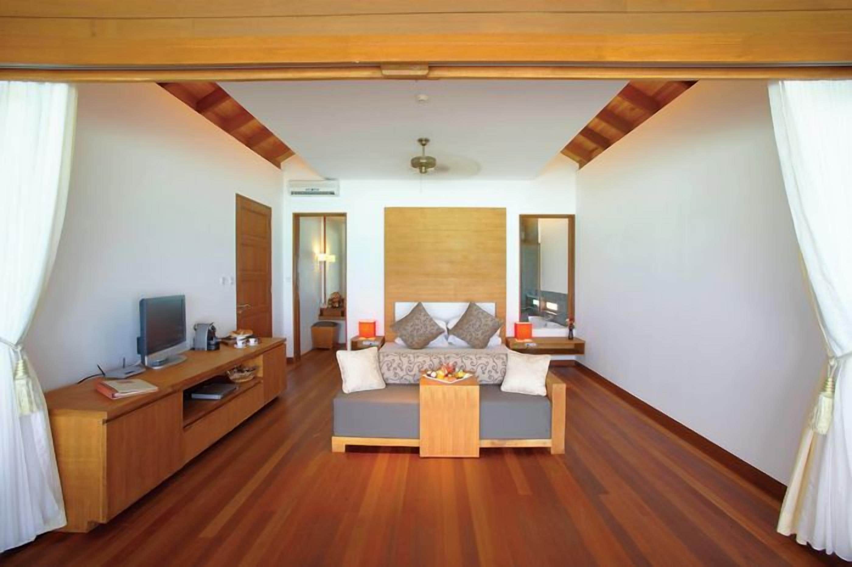 Une chambre à coucher avec un lit en bois, une télévision, un bureau et un miroir.