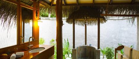 A bathroom with a wooden vanity, a large mirror, and a view of the sea.