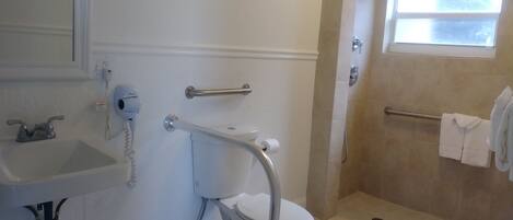 Un baño con inodoro, lavamanos y zona de ducha.