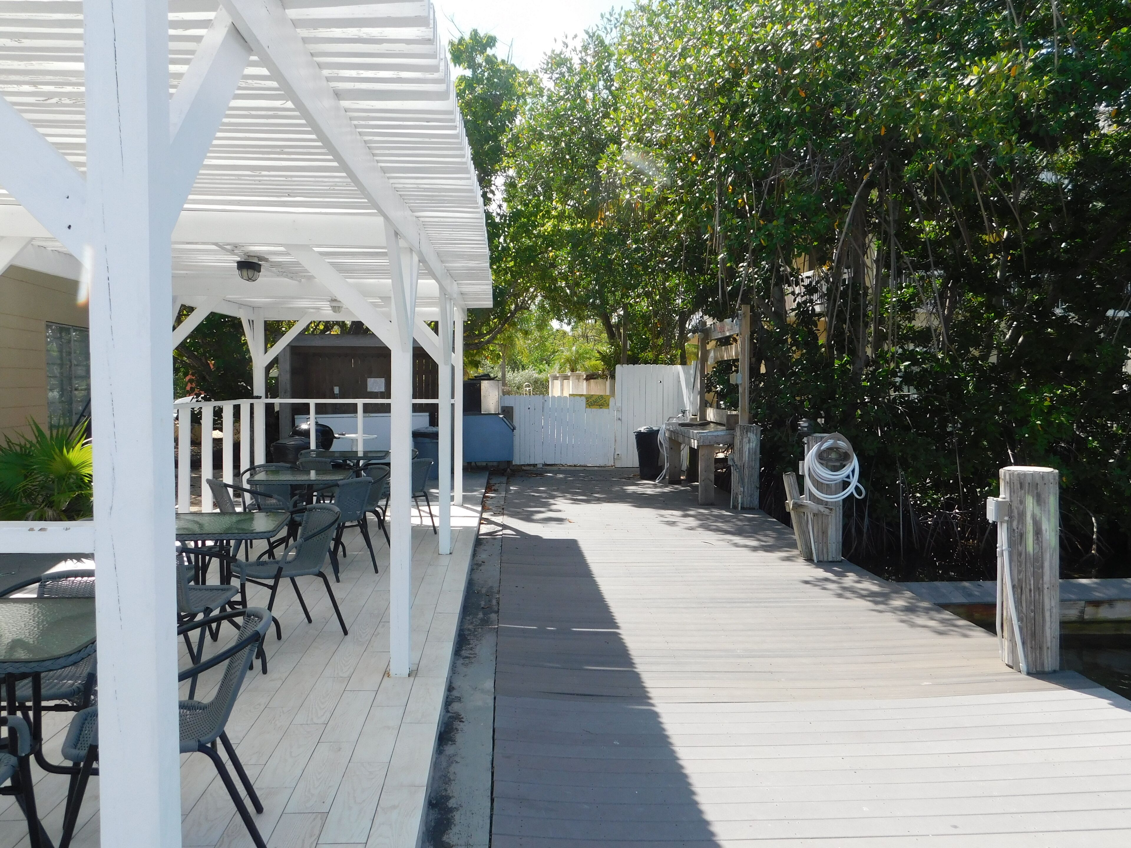 Un patio extérieur couvert, équipé de tables et de chaises, d’un barbecue et d’une terrasse en bois.