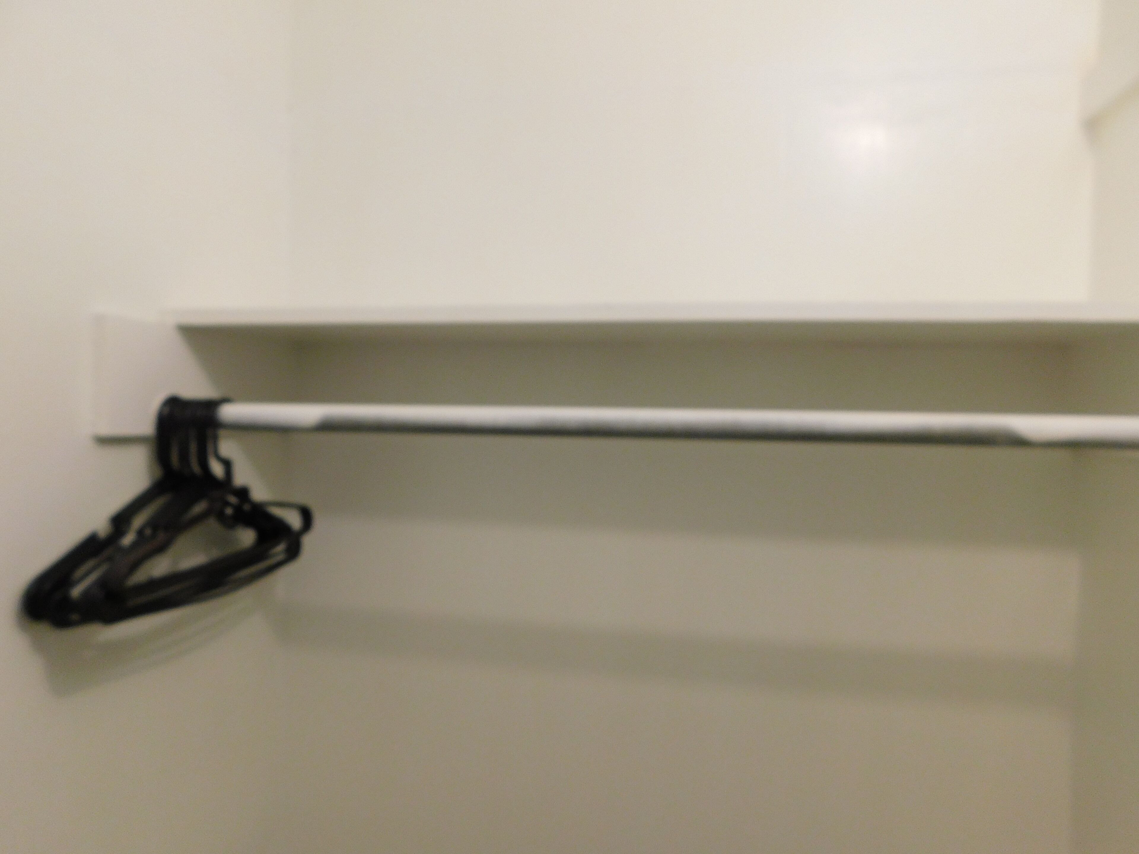 Un muro bianco con un appendiabiti nero e un porta asciugamani bianco.