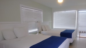 Une chambre d’hôtel avec deux lits, du linge de lit blanc et une touche de couleur bleue.