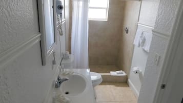 A bathroom with a sink, toilet, and shower area.