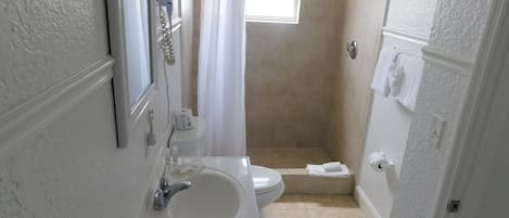A bathroom with a sink, toilet, and shower area.