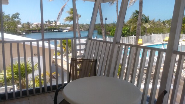 Un espace extérieur abrité offrant une vue sur une piscine et des palmiers.