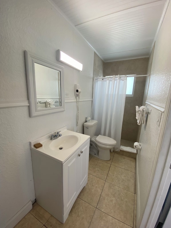 Un baño pequeño con tocador blanco, inodoro y zona de ducha.