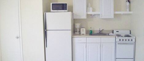 A compact kitchen with a refrigerator, microwave, toaster, sink, and stove.