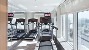 Un gimnasio con cintas de correr, una bicicleta estática y una máquina de remo.