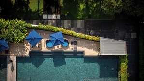 Zona de piscina en la azotea con sombrillas azules y un diseño arquitectónico moderno.