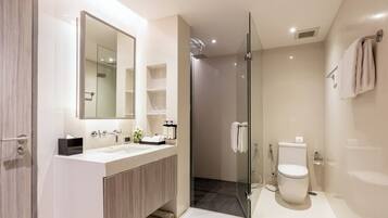 A modern bathroom with a glass-enclosed shower, a large mirror, and a vanity with a sink and storage.